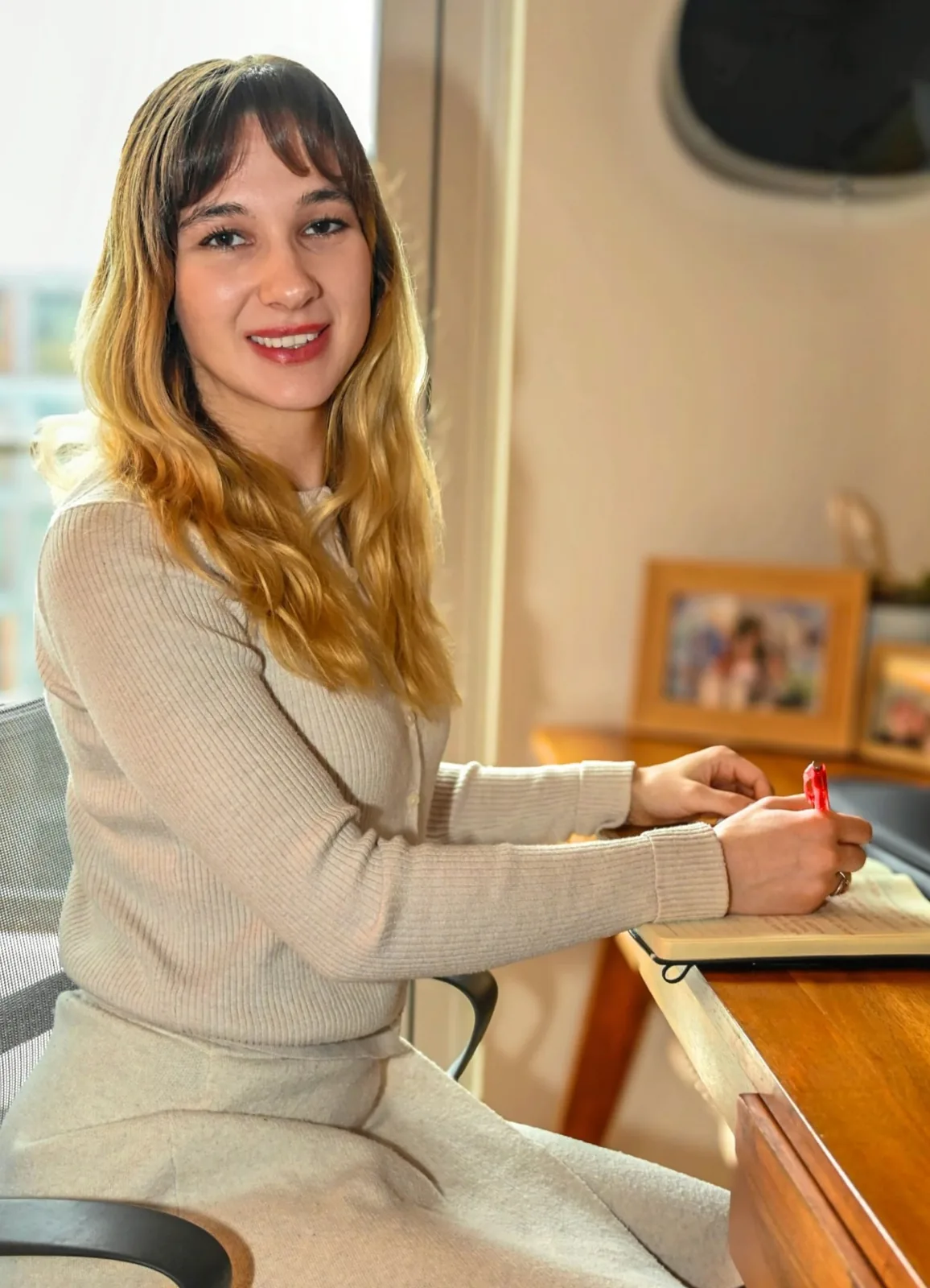 Haile sitting at a desk, smiling warmly while writing in a notebook