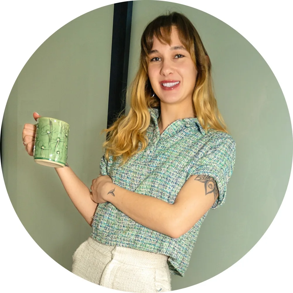 Haile smiling, holding a handmade green mug