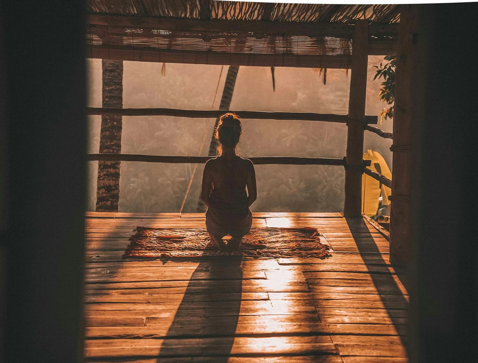 A woman sitting quietly on an open-air deck at sunrise in Costa Rica